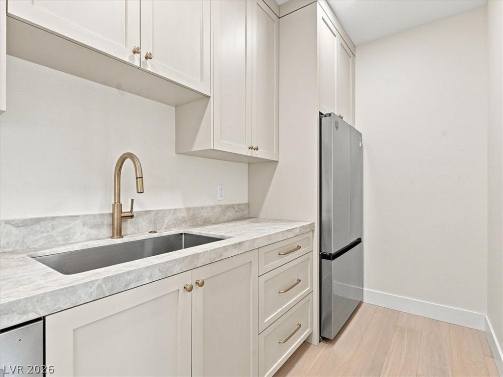 Shaker cabinets and stone countertops provide functional elegance alongside light wood flooring.