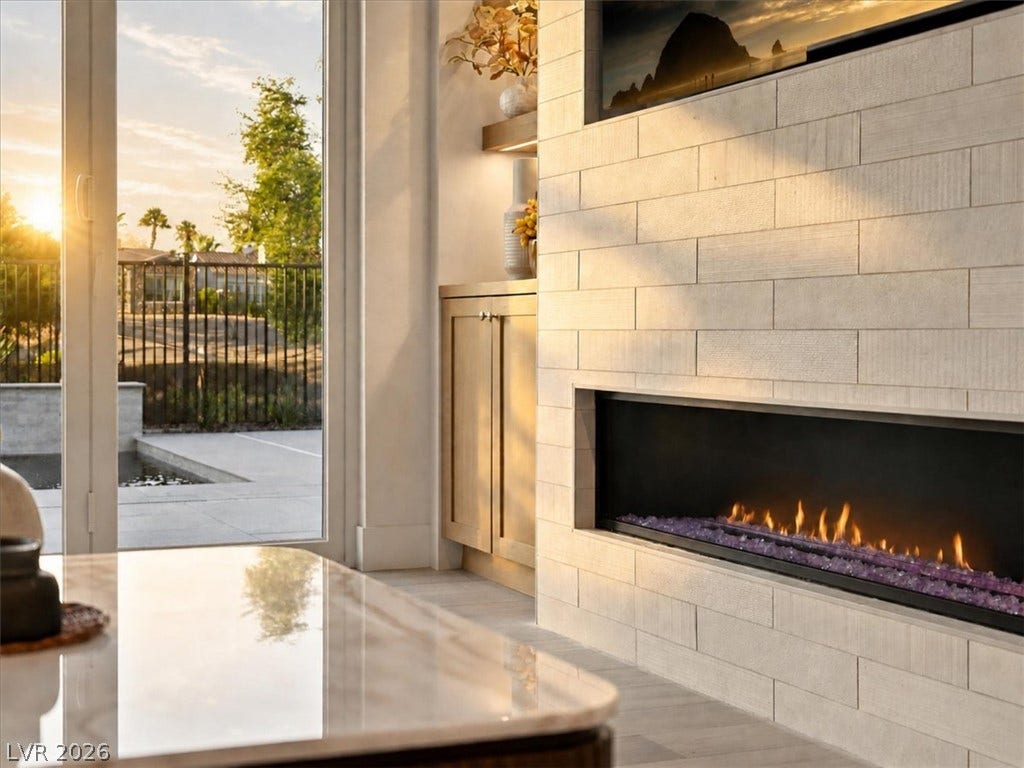 A modern tiled fireplace anchors the room, framed by glass doors opening to the patio.