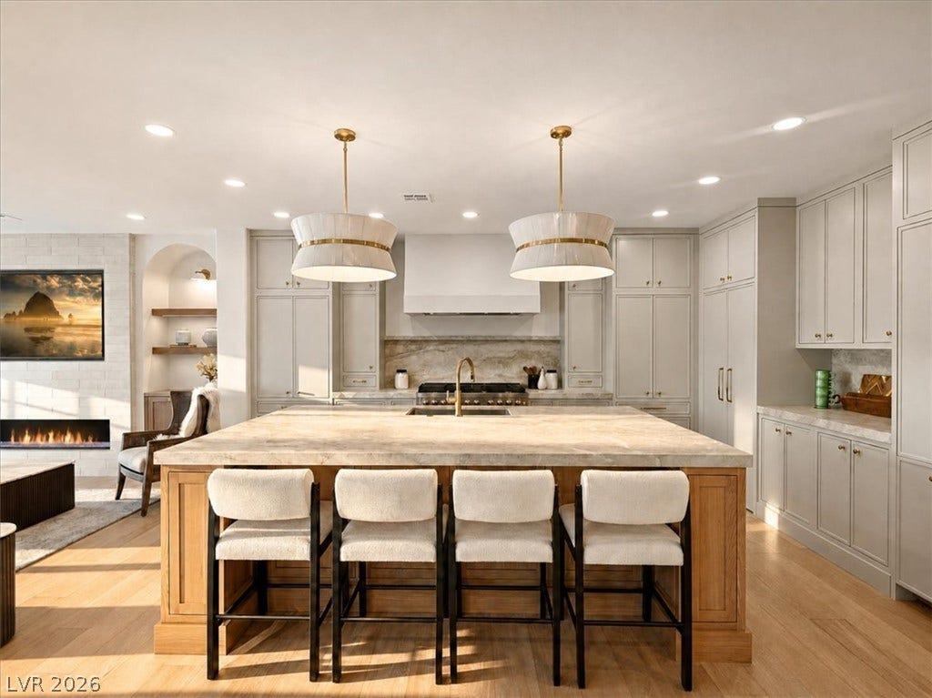 Fine craftsmanship anchors this culinary space, highlighted by a substantial stone-topped island and warm hardwood flooring.