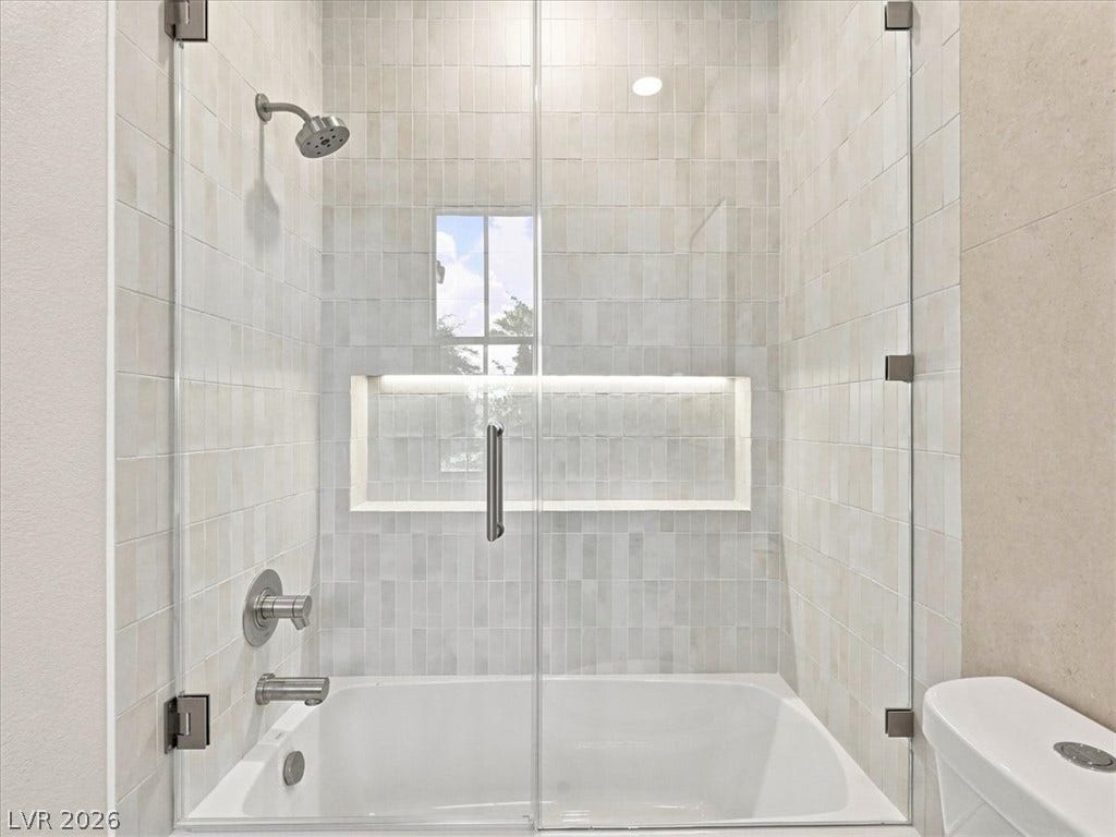 Modern tiled shower enclosure features a built-in tub and sleek glass door.