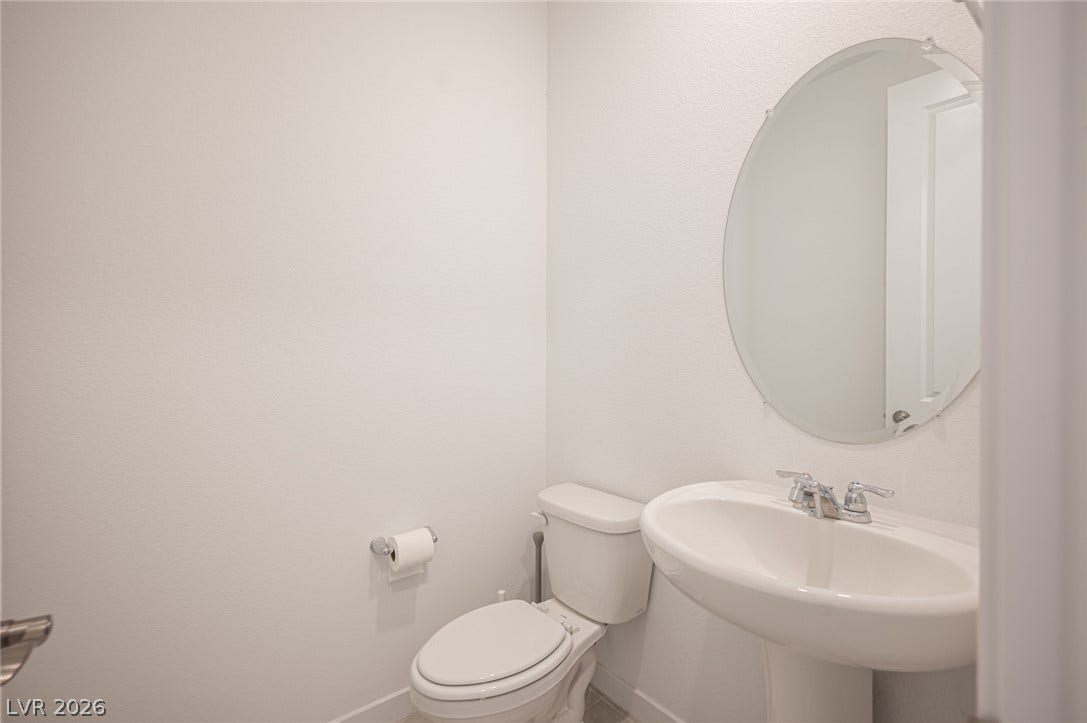 2545 Monolith Street, Las Vegas, NV 89138 A classic pedestal sink paired with a round mirror anchors this minimalist powder room.