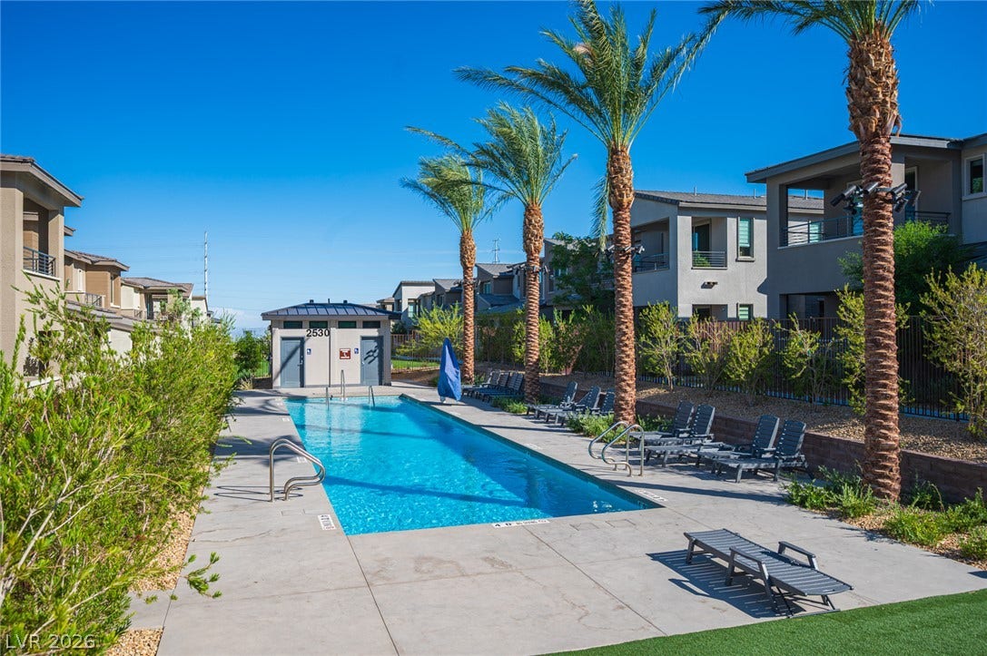 2545 Monolith Street, Las Vegas, NV 89138 Mature palm trees frame a sparkling swimming pool situated within a modern residential community.