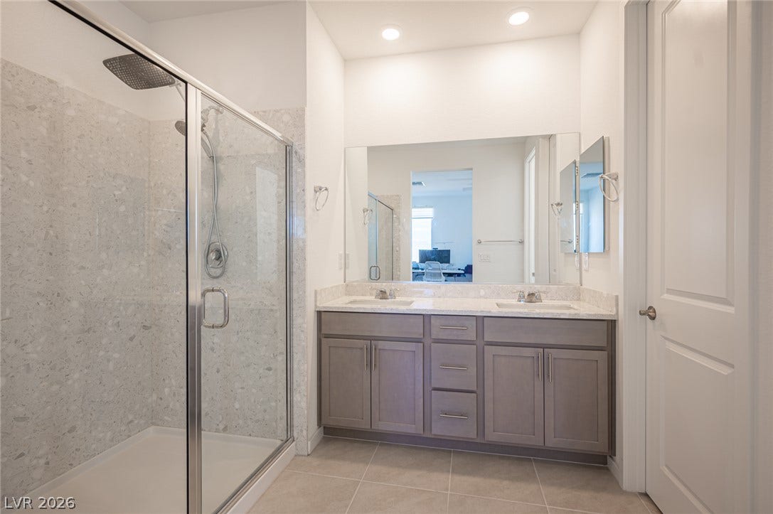 2545 Monolith Street, Las Vegas, NV 89138 A modern double vanity stands adjacent to a spacious glass-enclosed shower with custom tile surrounds.