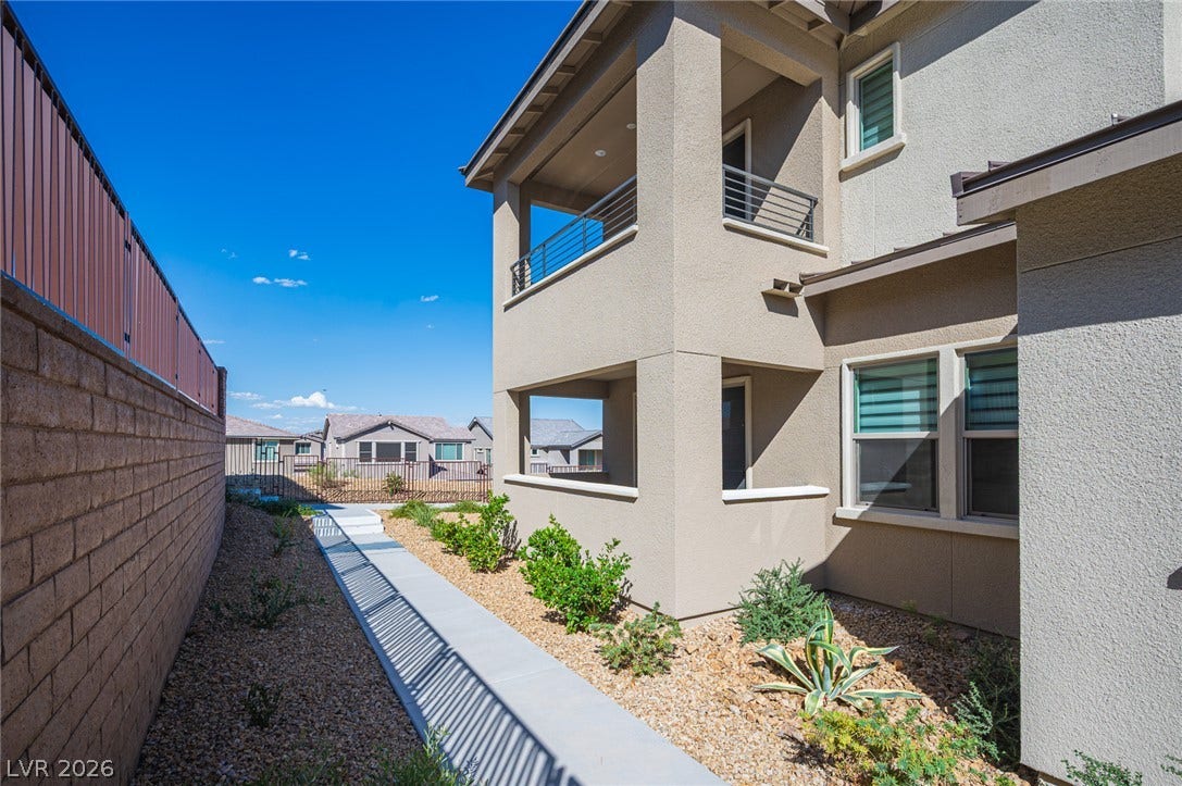 2545 Monolith Street, Las Vegas, NV 89138 A concrete walkway borders the stucco exterior alongside a secure block wall.