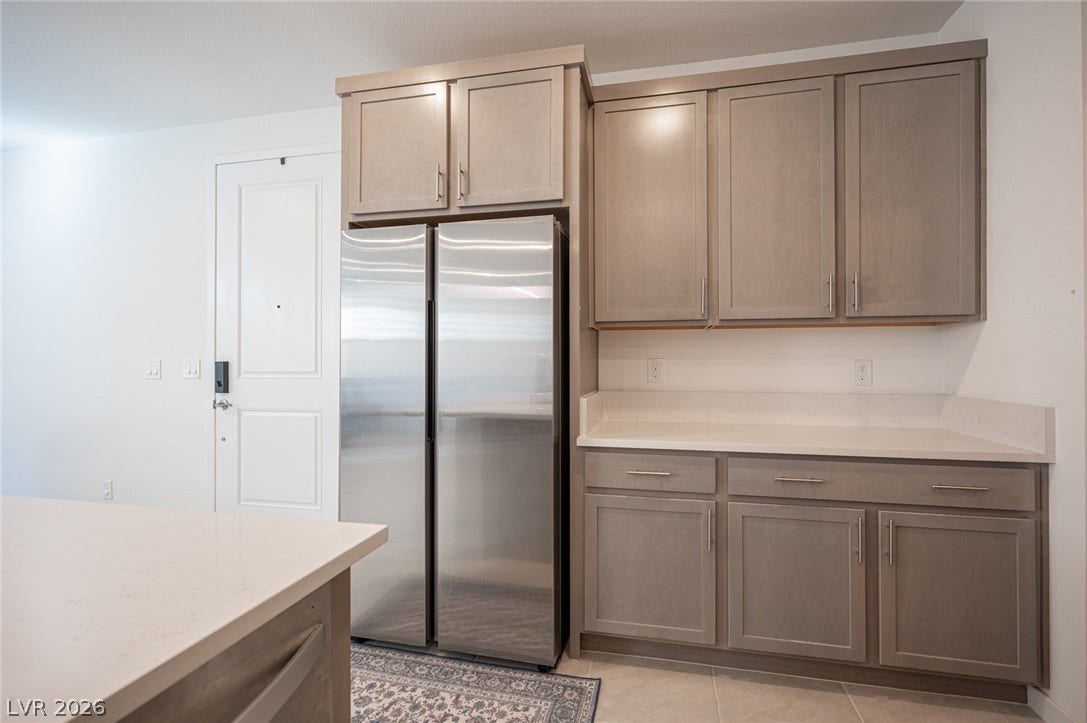 2545 Monolith Street, Las Vegas, NV 89138 Ample custom cabinetry and stone countertops flank a modern stainless steel refrigerator.
