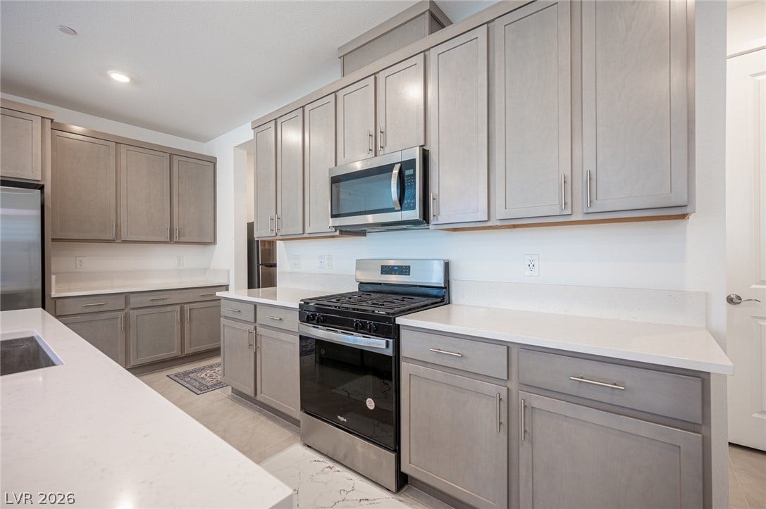 2545 Monolith Street, Las Vegas, NV 89138 Gleaming stone countertops and classic cabinetry elevate this modern kitchen workspace.