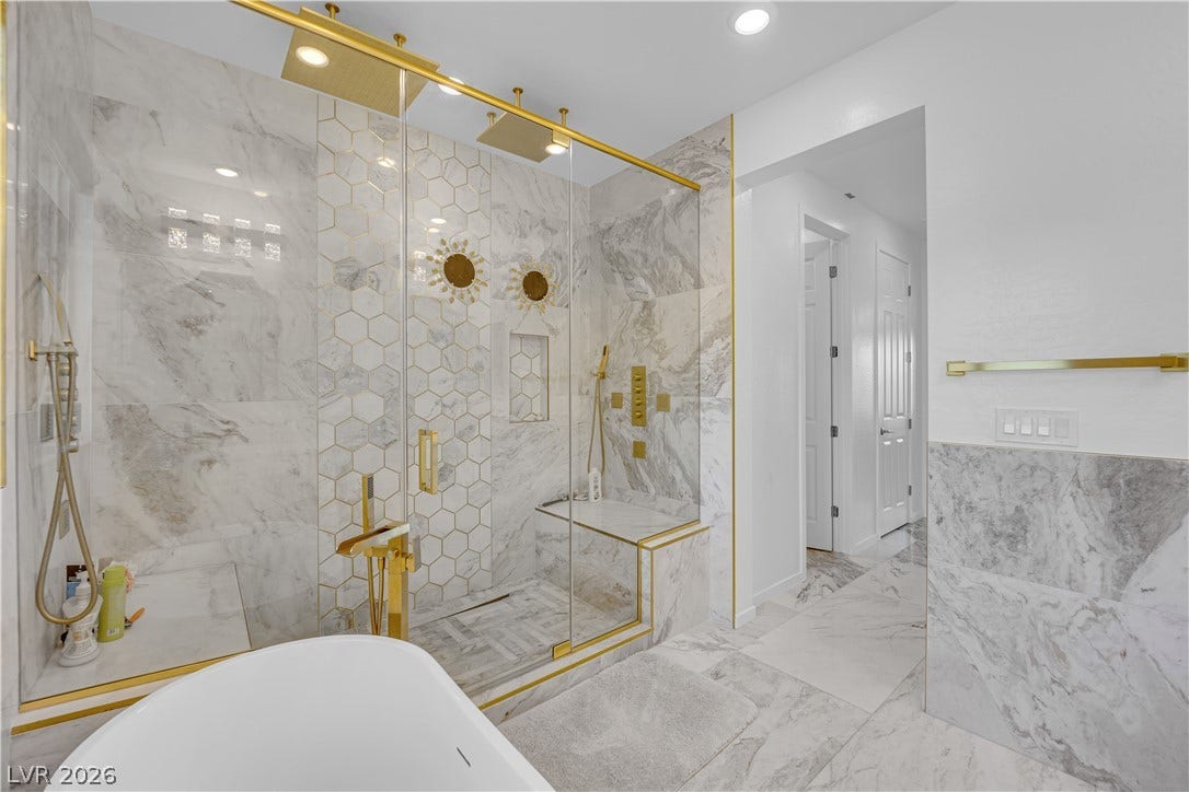 12415 Aster Hills Avenue, Las Vegas, NV 89138 Exquisite marble tile walls and elegant gold fixtures define this spa-like bathroom space.