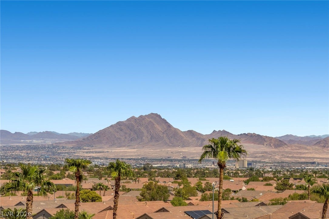 1976 Peaceful Mesa Court, Henderson, NV 89052 Majestic mountain ridges and neighborhood rooftops frame the distant horizon under clear blue skies.