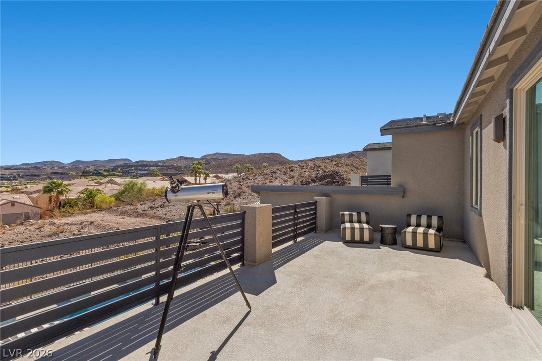 1976 Peaceful Mesa Court, Henderson, NV 89052 An elevated stone balcony overlooks panoramic desert ridges under clear blue skies.