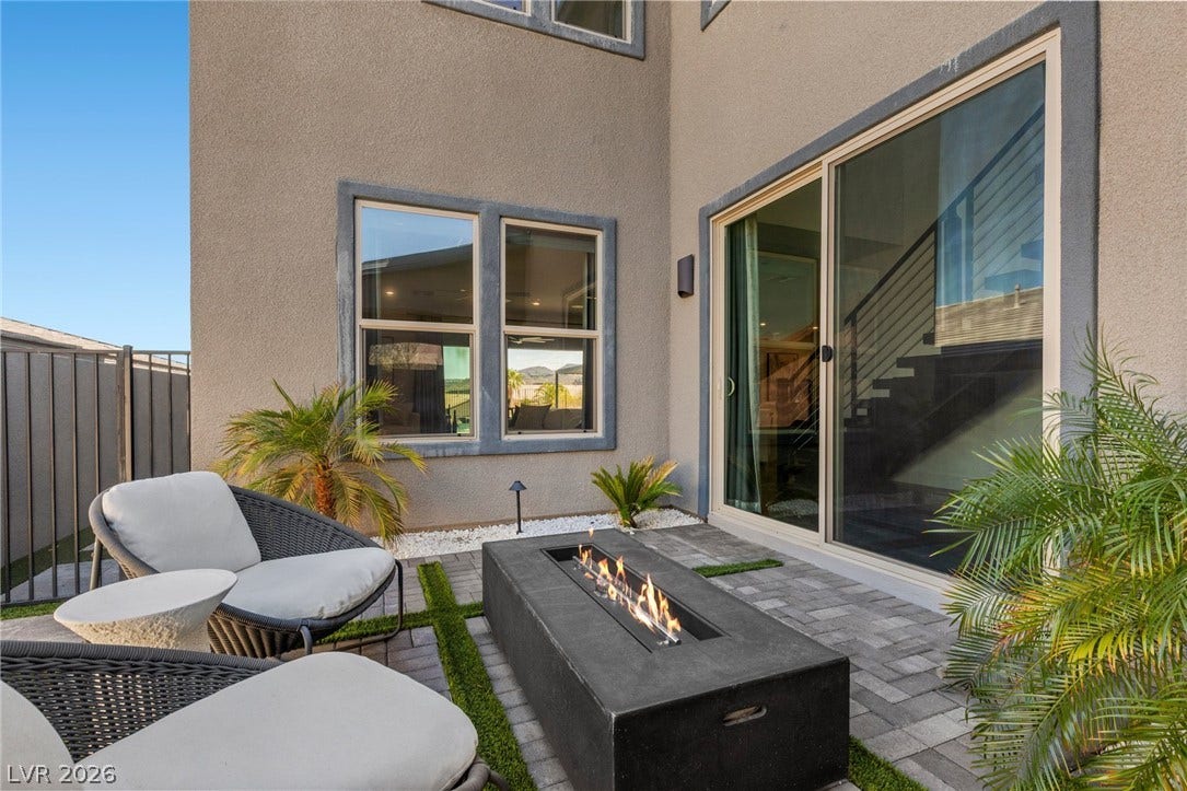 1976 Peaceful Mesa Court, Henderson, NV 89052 A modern gas fire pit highlights this paved outdoor patio area next to stucco walls.