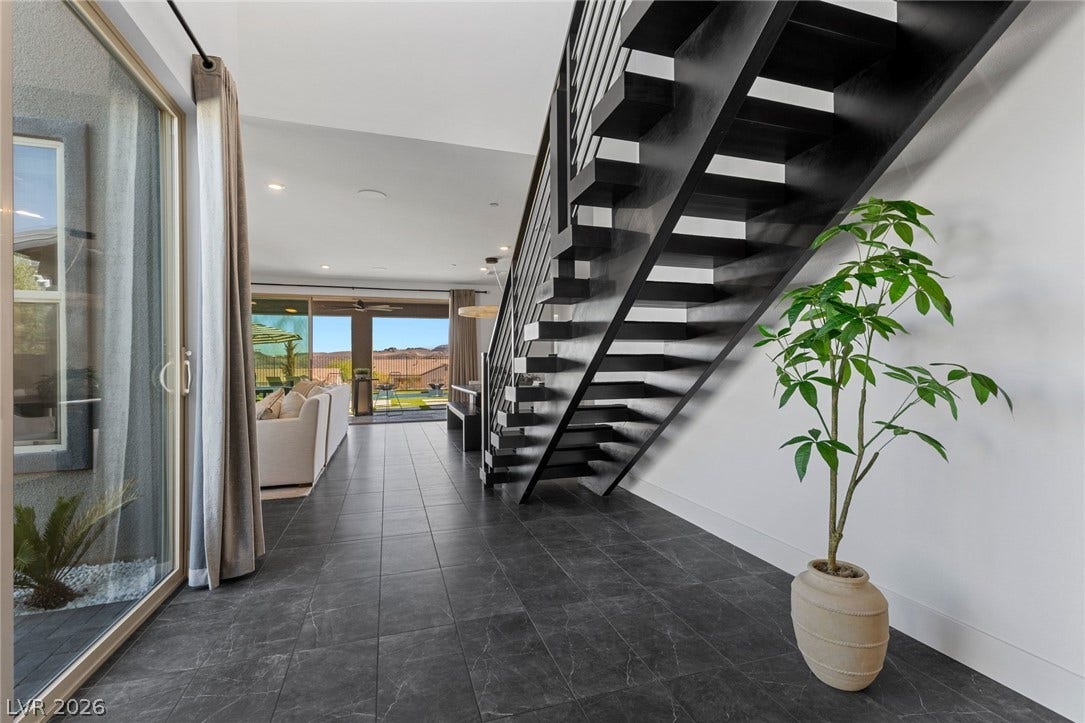 1976 Peaceful Mesa Court, Henderson, NV 89052 Dark stone tile flooring and a sculptural open-tread staircase define this modern entryway.
