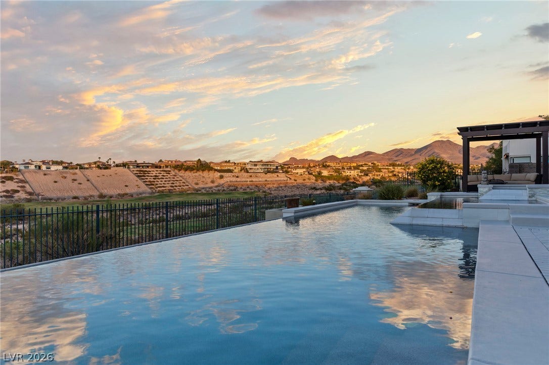1358 Opal Valley Street, Henderson, NV 89052 An infinity pool with desert hills and mountain views under a twilight sky.