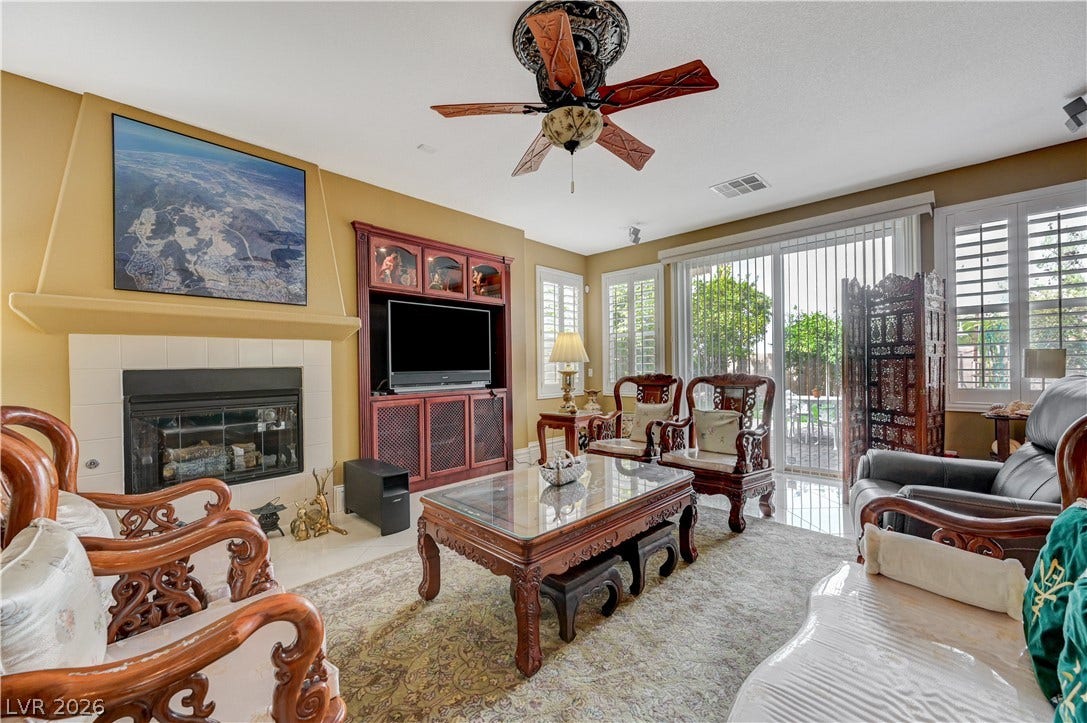 218 Crooked Putter Drive, Las Vegas, NV 89148 A spacious living room displays a tiled fireplace alongside sliding glass doors to the patio.