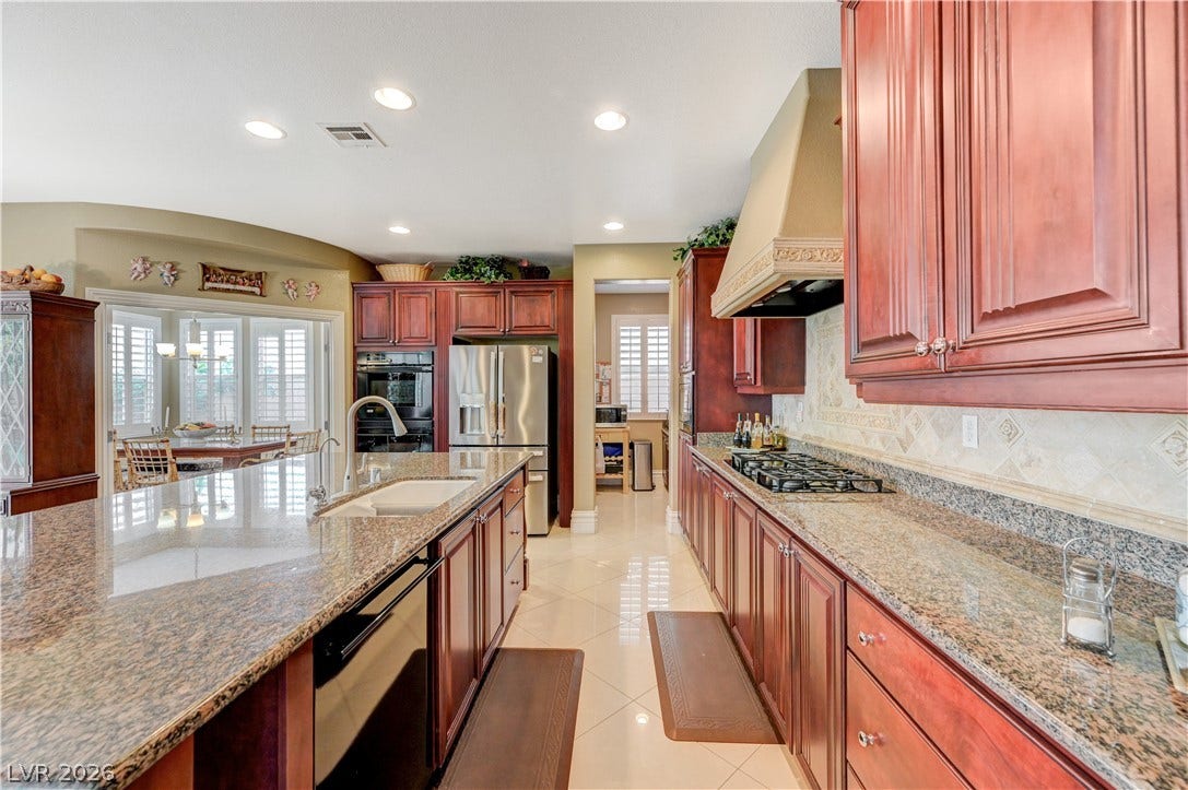 218 Crooked Putter Drive, Las Vegas, NV 89148 Polished stone countertops pair beautifully with rich wood cabinetry and clean tiled flooring.