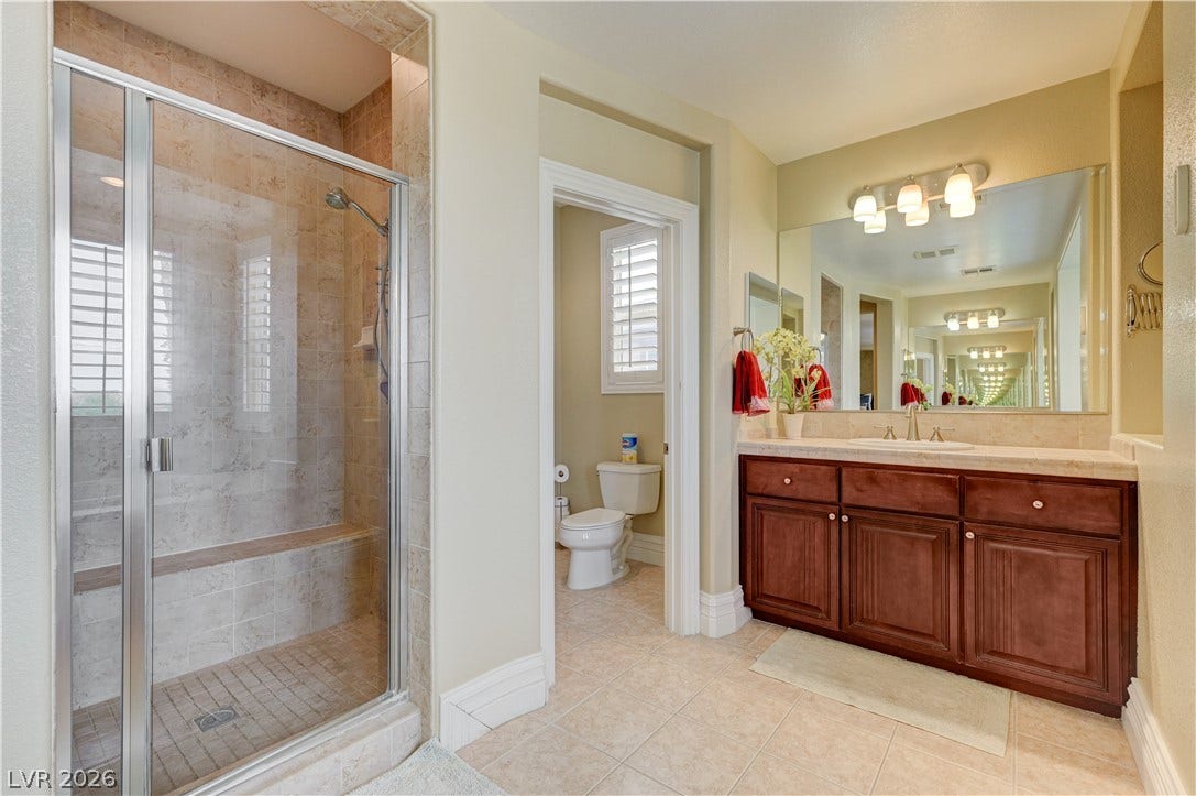 218 Crooked Putter Drive, Las Vegas, NV 89148 Fine tile flooring pairs with a glass-enclosed shower and wood vanity in this master bath.