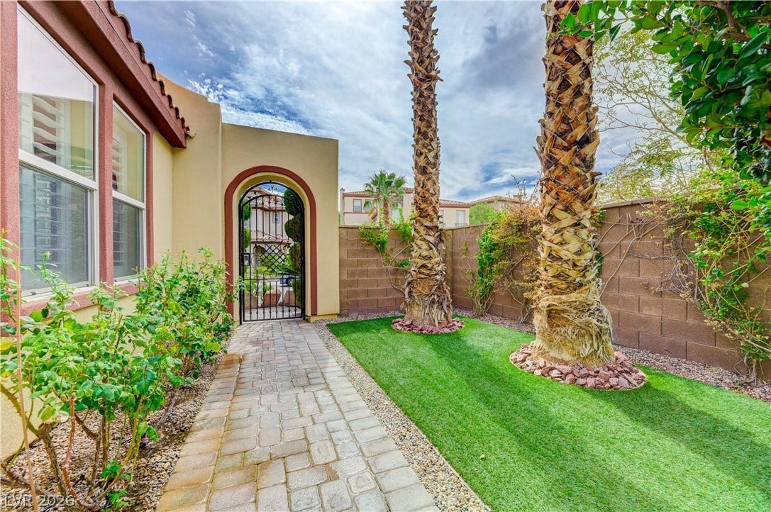 218 Crooked Putter Drive, Las Vegas, NV 89148 A paved path leads to a gated courtyard entry flanked by towering palm trees.