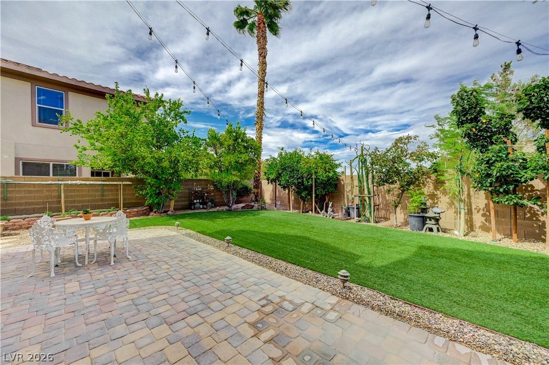 218 Crooked Putter Drive, Las Vegas, NV 89148 A spacious stone paver patio overlooks a manicured green lawn enclosed by privacy fencing.