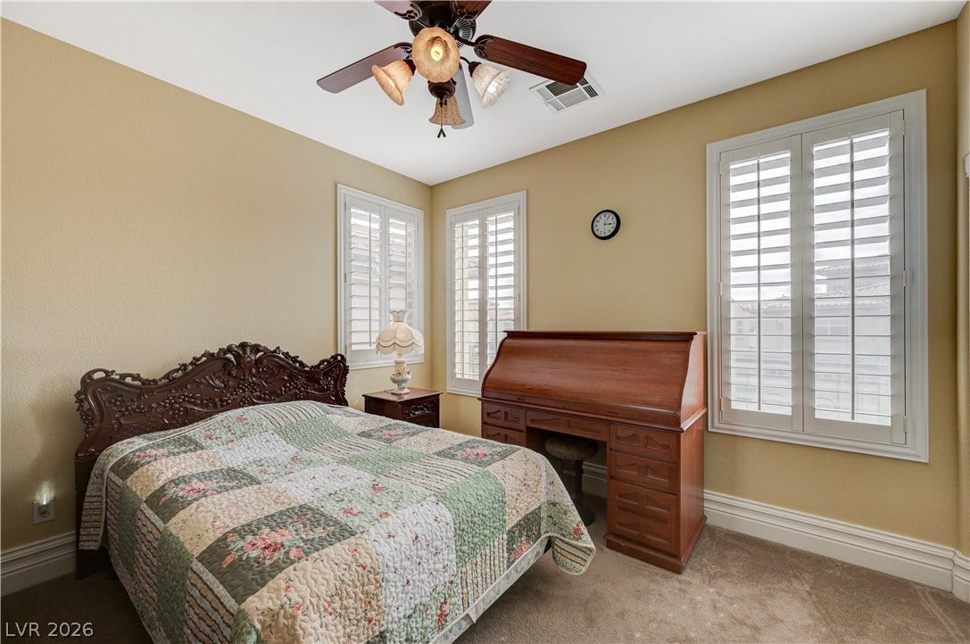 218 Crooked Putter Drive, Las Vegas, NV 89148 Classic plantation shutters filter natural light across the comfortable carpeted bedroom.