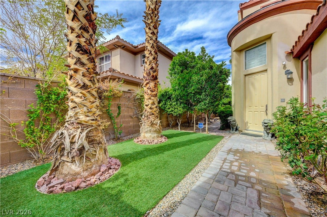 218 Crooked Putter Drive, Las Vegas, NV 89148 A paved walkway winds past towering palm trees to a private entry tucked behind privacy walls.