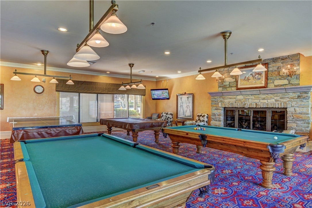 218 Crooked Putter Drive, Las Vegas, NV 89148 An inviting stone fireplace anchors this expansive recreational space featuring detailed crown molding.