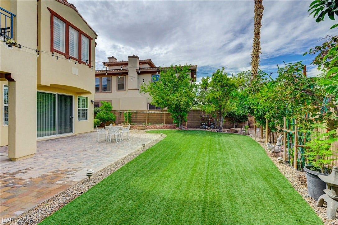 218 Crooked Putter Drive, Las Vegas, NV 89148 A manicured green lawn borders a spacious paved patio ideal for outdoor relaxation.