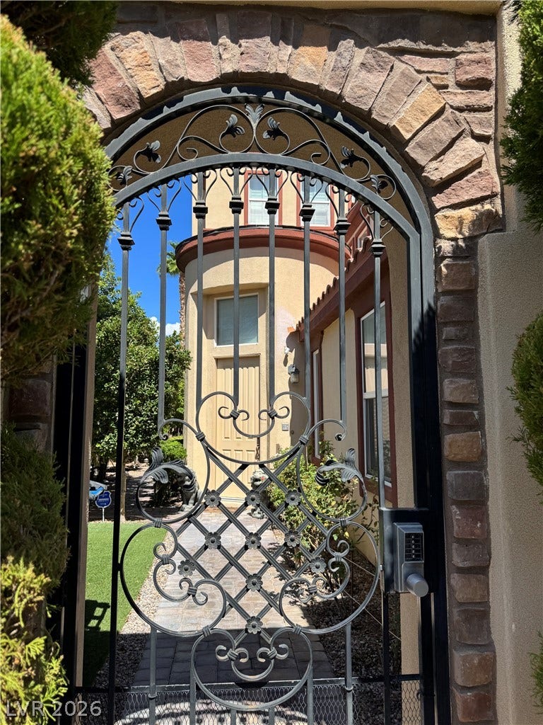 218 Crooked Putter Drive, Las Vegas, NV 89148 An ornate wrought iron gate set within a stone archway leads into the courtyard.