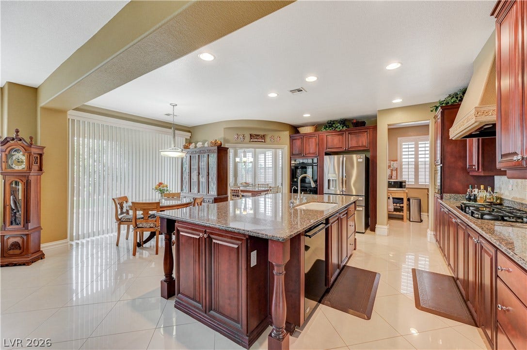 218 Crooked Putter Drive, Las Vegas, NV 89148 Polished tile flooring and rich wood cabinetry define this open culinary space.