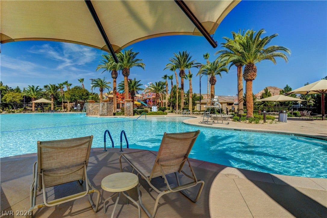 218 Crooked Putter Drive, Las Vegas, NV 89148 Shaded lounge areas border a resort-style swimming pool lined with mature palm trees.