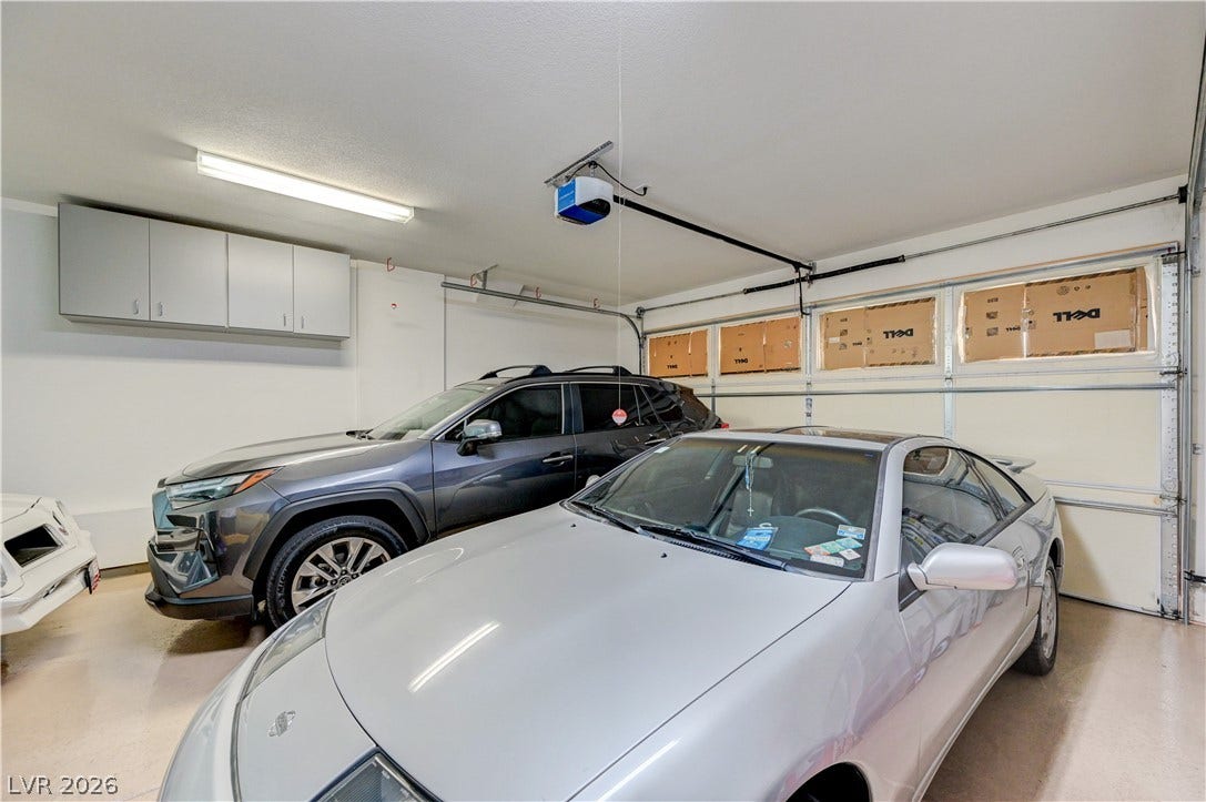 218 Crooked Putter Drive, Las Vegas, NV 89148 A spacious garage features durable finished flooring and integrated overhead storage cabinets.
