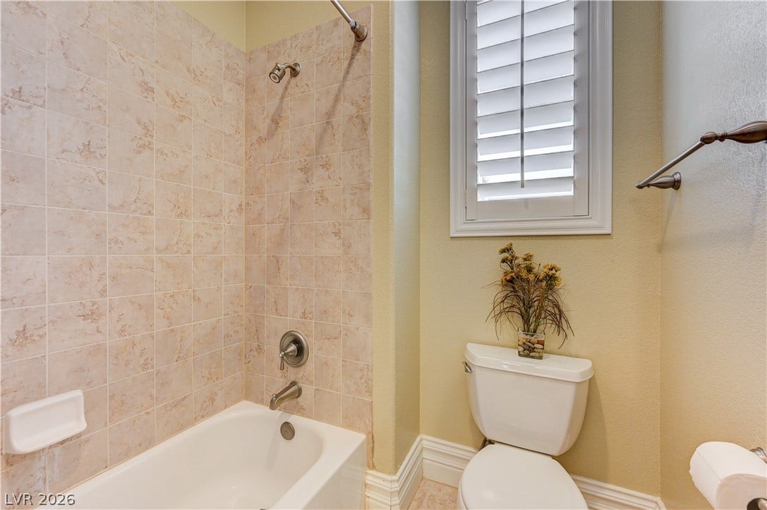 218 Crooked Putter Drive, Las Vegas, NV 89148 Tiled tub surrounds meet classic plantation shutters in this functional bathroom layout.
