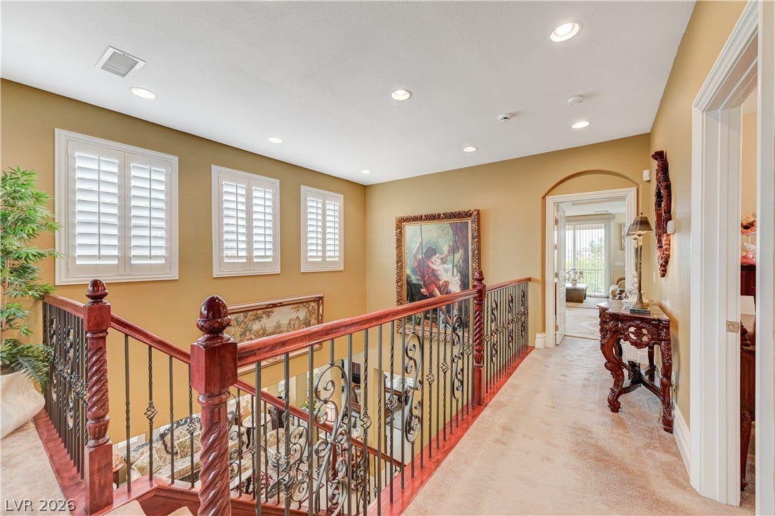 218 Crooked Putter Drive, Las Vegas, NV 89148 An upper hallway features carpeted flooring and ornate wrought-iron railings overlooking the lower level.