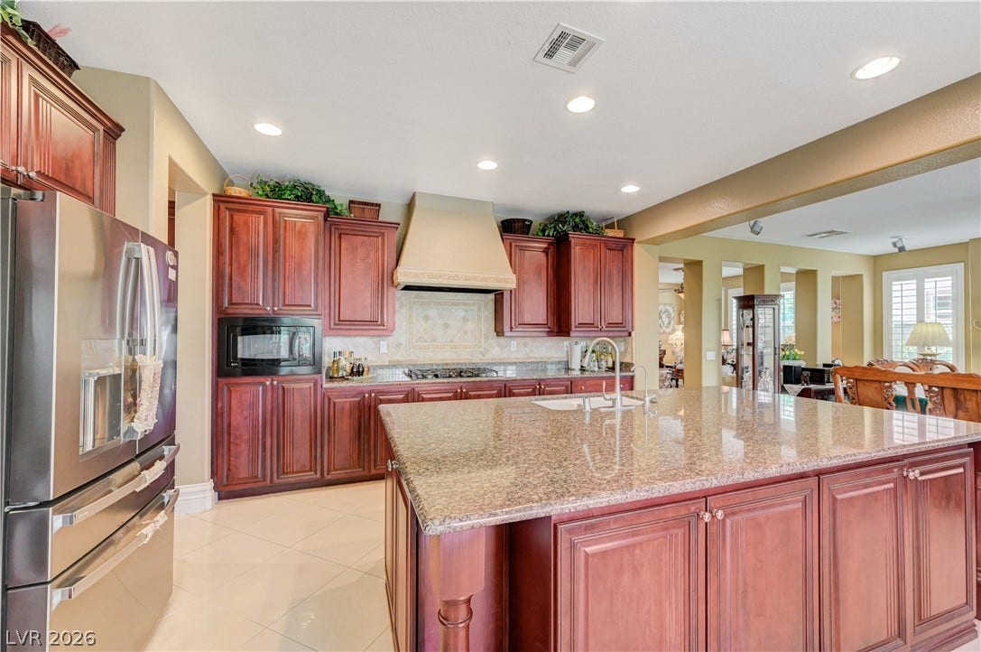 218 Crooked Putter Drive, Las Vegas, NV 89148 Rich wood cabinetry and expansive granite countertops highlight this spacious kitchen design.