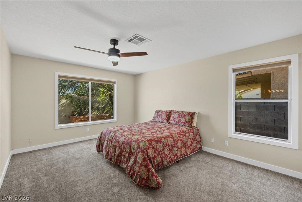 2432 Millcroft Drive, Henderson, NV 89074 Plush carpet and large windows frame this comfortable bedroom space.