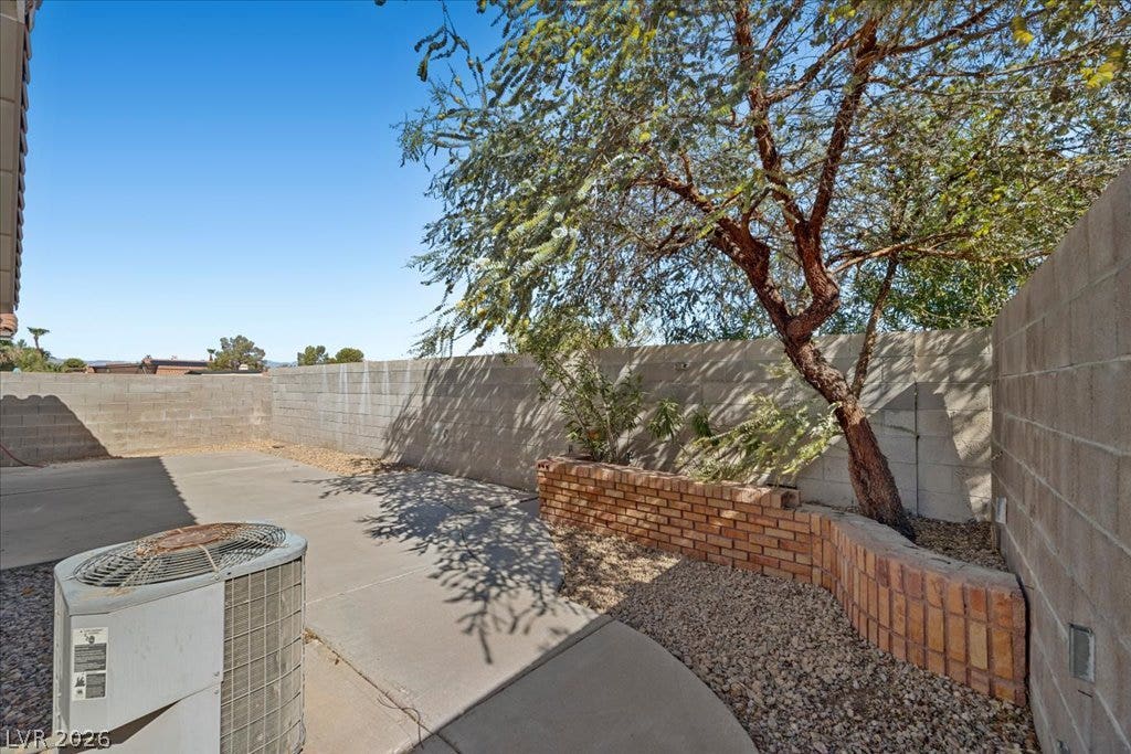 2432 Millcroft Drive, Henderson, NV 89074 A concrete patio area is enclosed by block privacy walls and shaded by mature trees.