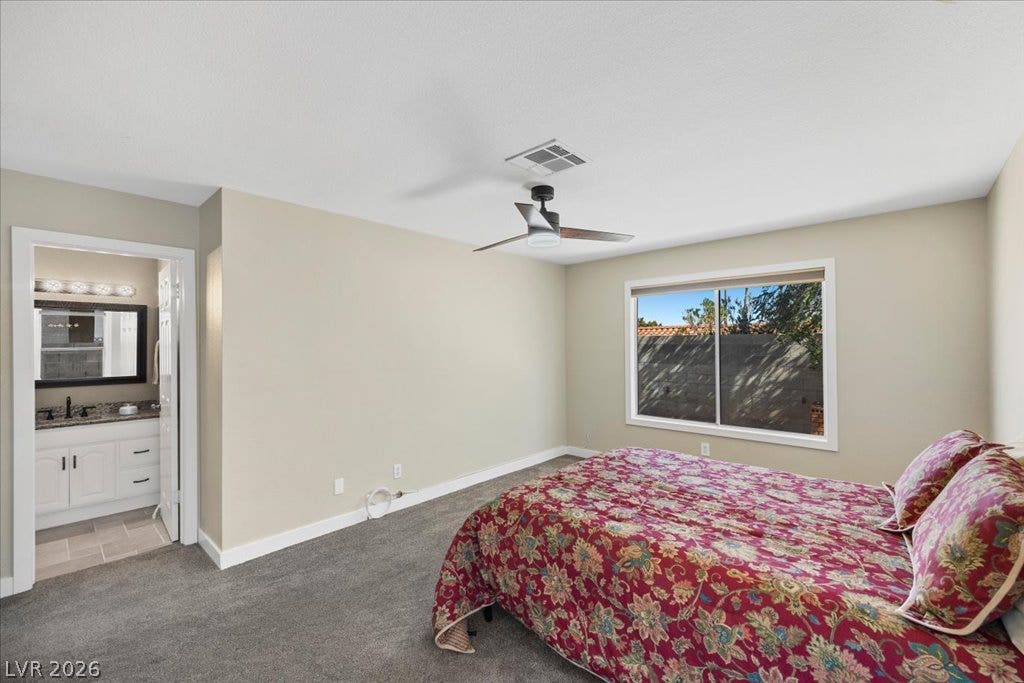 2432 Millcroft Drive, Henderson, NV 89074 An ensuite bathroom adjoins this comfortable bedroom with soft carpeting and a wide window.