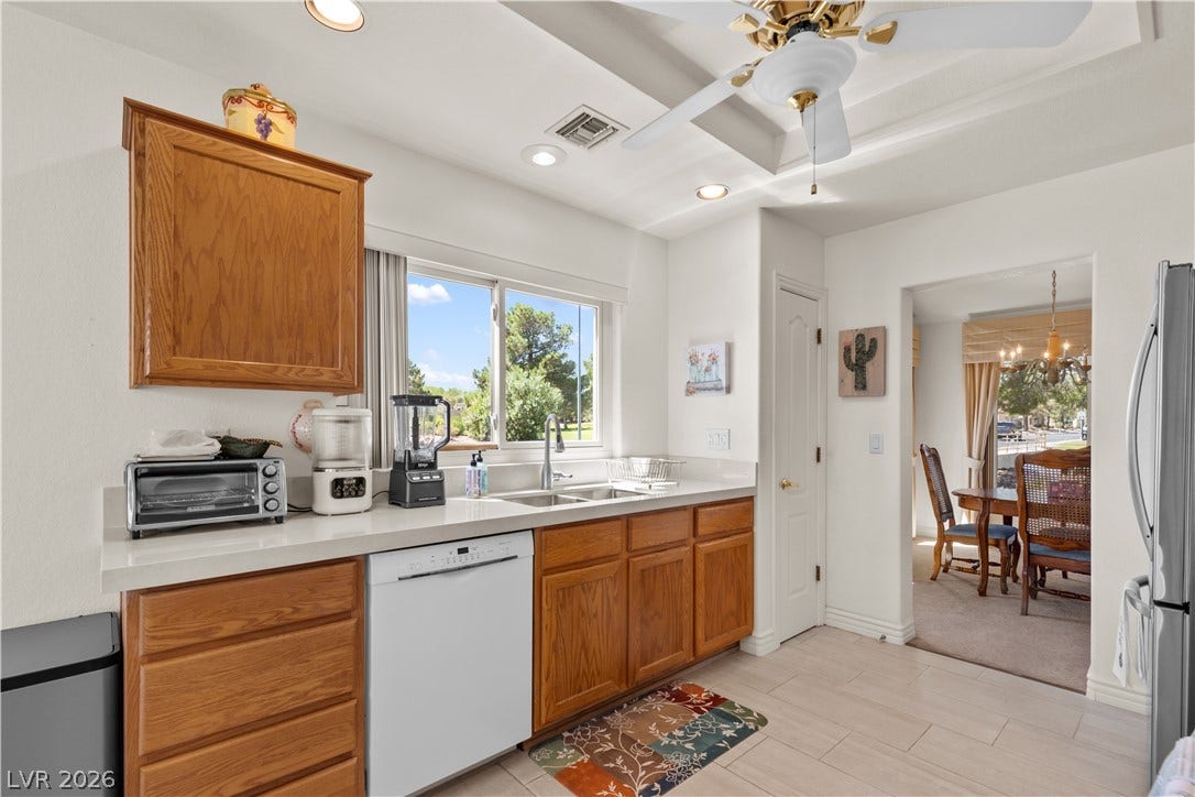 A sunny kitchen features light-toned tile flooring, warm wood cabinetry, and an adjoining dining space.