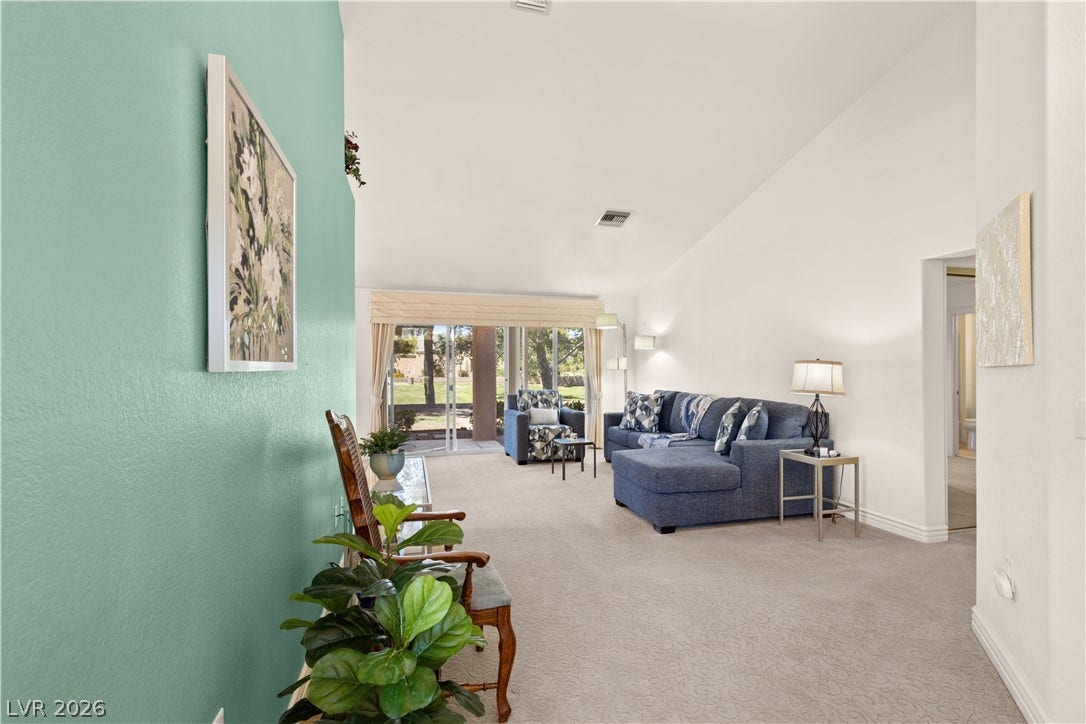 Vaulted ceilings and plush carpeting enhance this welcoming living space with glass sliders.