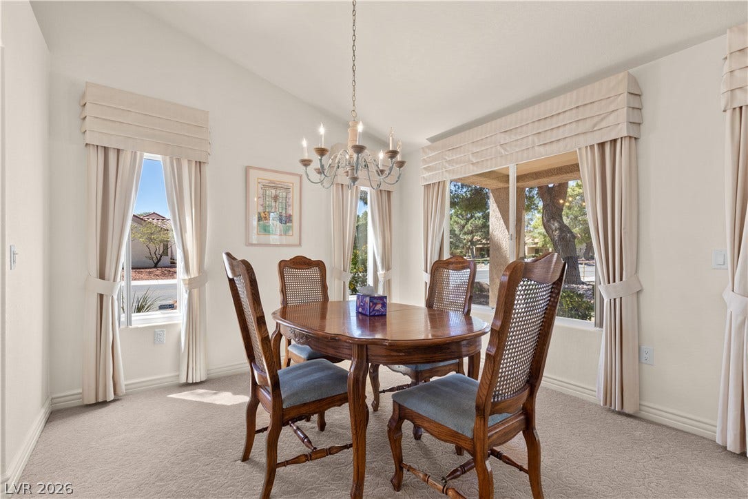 Vaulted ceilings and plush carpeting enhance the formal dining space, illuminated by classic fixtures.