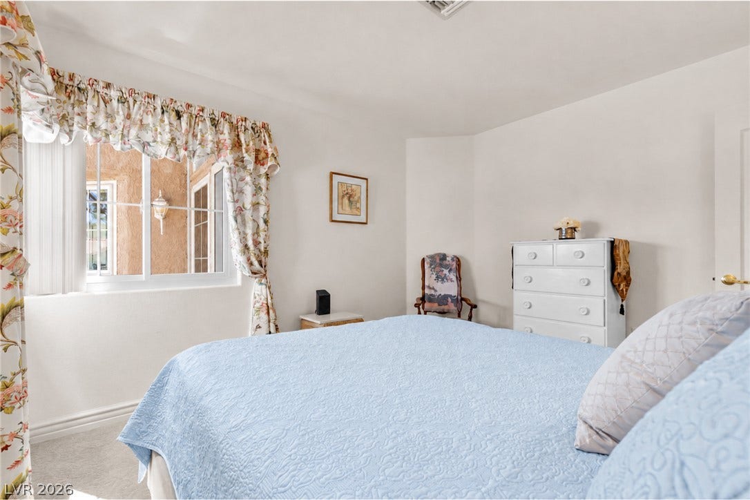 Soft carpet flooring and natural light from a large window define this bedroom.