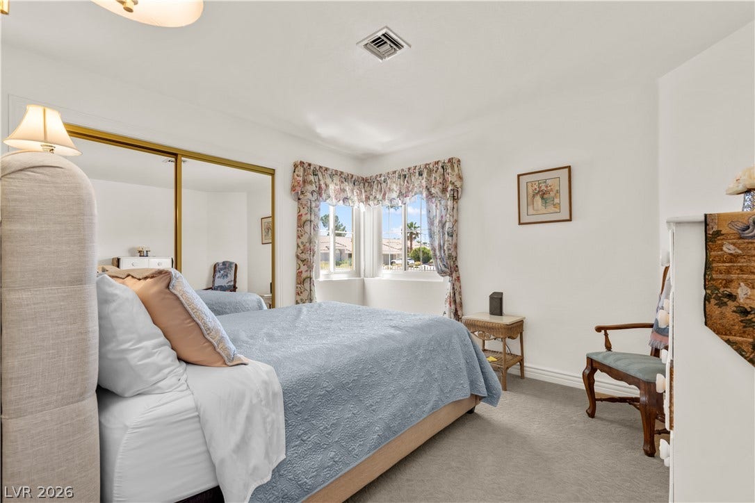Mirrored closet doors and corner windows enhance this comfortable carpeted bedroom.