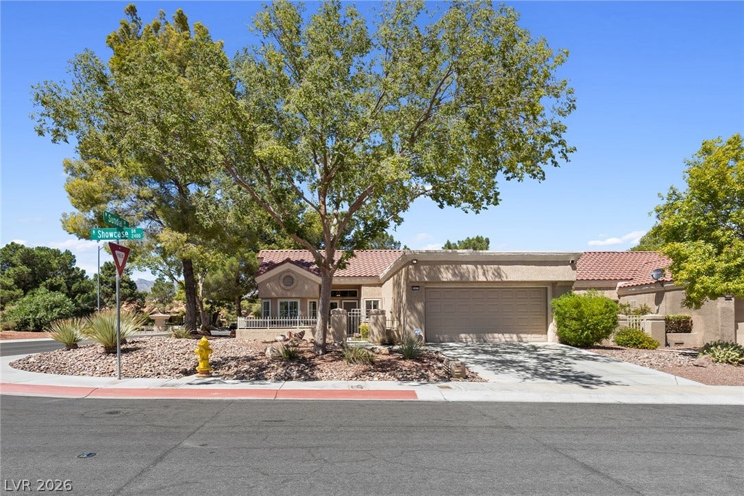 Mature trees shade the front yard of this classic single-story home with a tiled roof.