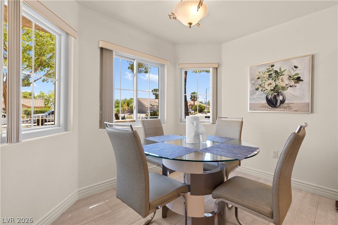 Sunlight pours through bay windows into a cozy dining space with light wood-style flooring.