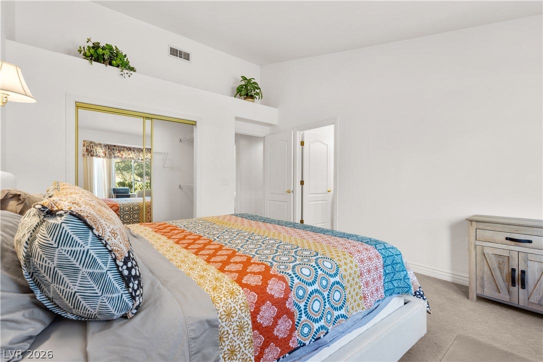 High vaulted ceilings and soft carpet floorings define this airy main bedroom space.