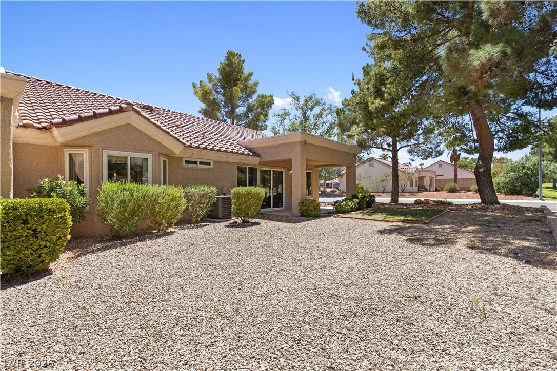 Mature trees shade the low-maintenance gravel yard surrounding this classic tile-roof residence.