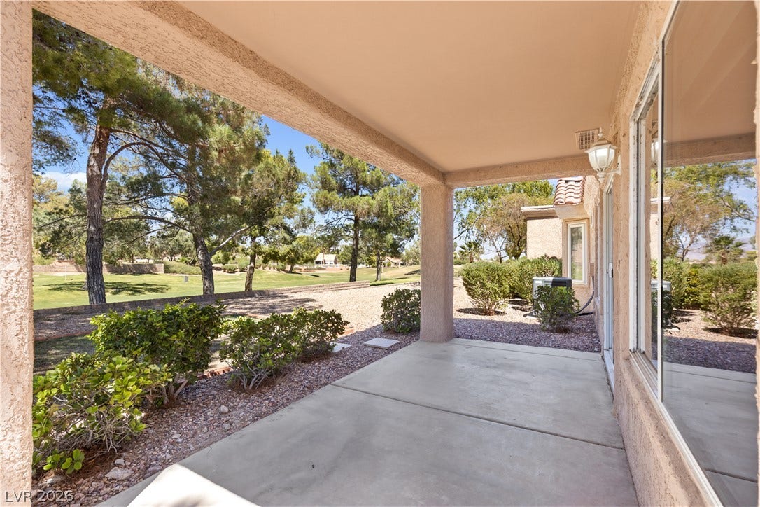 An inviting covered patio looks out over mature trees and a lush green golf course.