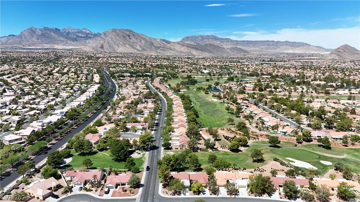 Panoramic neighborhood views unfold against a dramatic backdrop of rugged desert mountains.