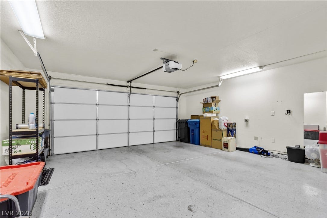 A spacious garage features durable concrete flooring and an automatic garage door opener.