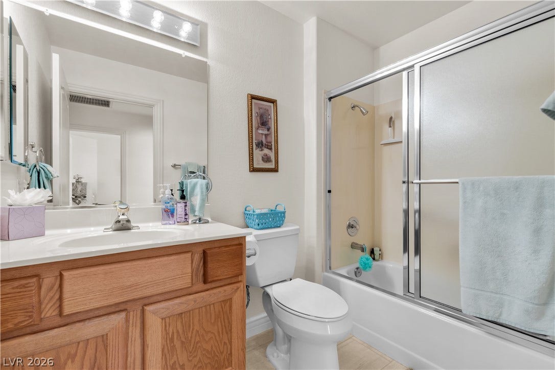 Warm wood cabinetry pairs with a clean tub shower combination in this full bathroom.