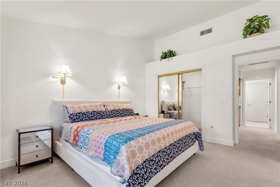 High ceilings and neutral carpeting define this restful sleeping space with mirrored closet doors.