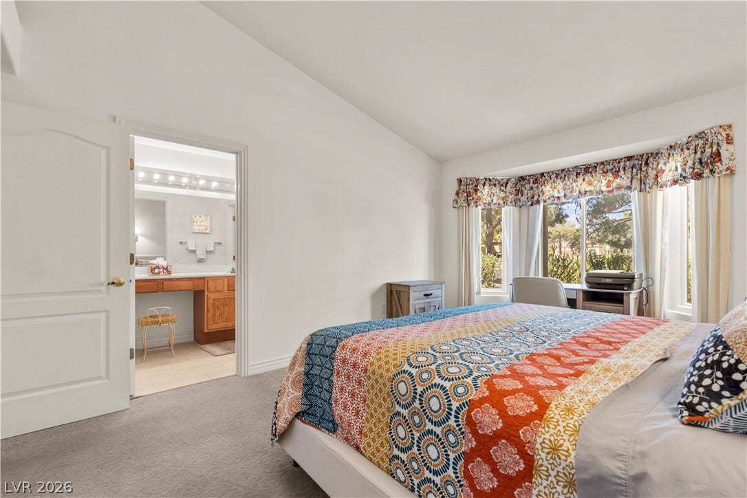 A spacious bedroom offers vaulted ceilings and views through a large bay window.